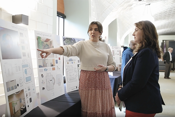 A student explains their project to an interested and listening community member