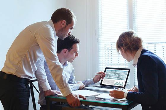 三名商务人士围着一台电脑的照片, 一起完成一个项目.